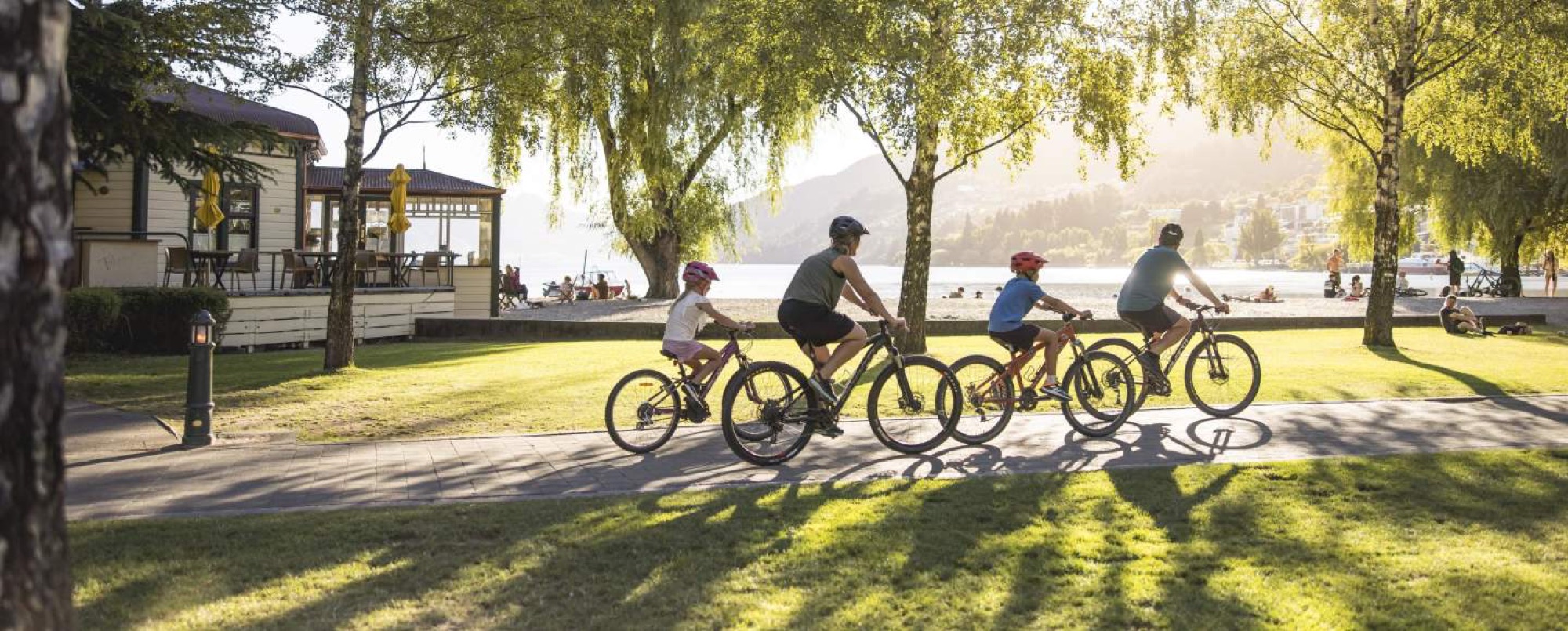 Family cycling along the lakefront in Queenstown