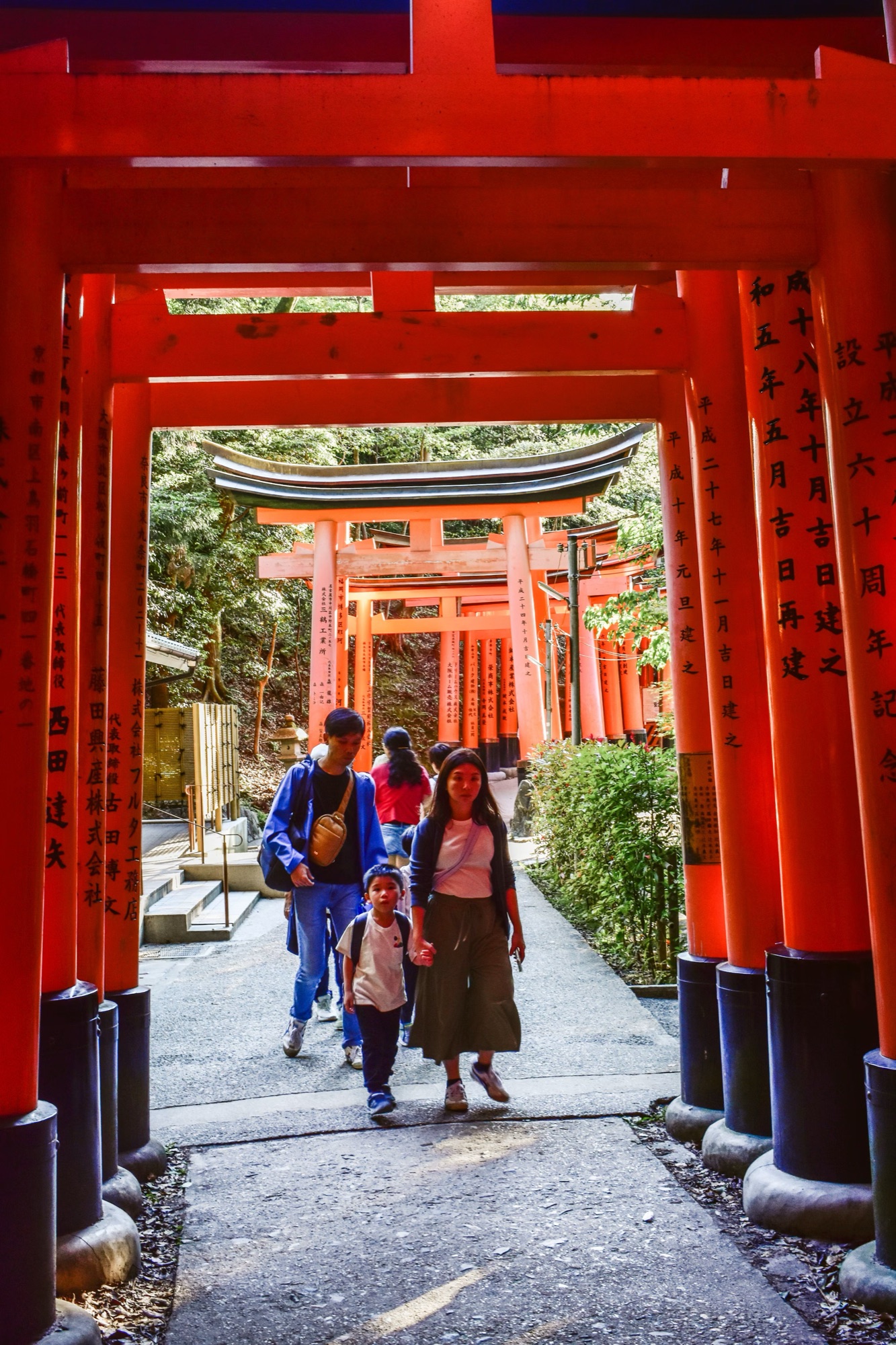 A family walking through the red torii gates at Fushimi Inari, Kyoto