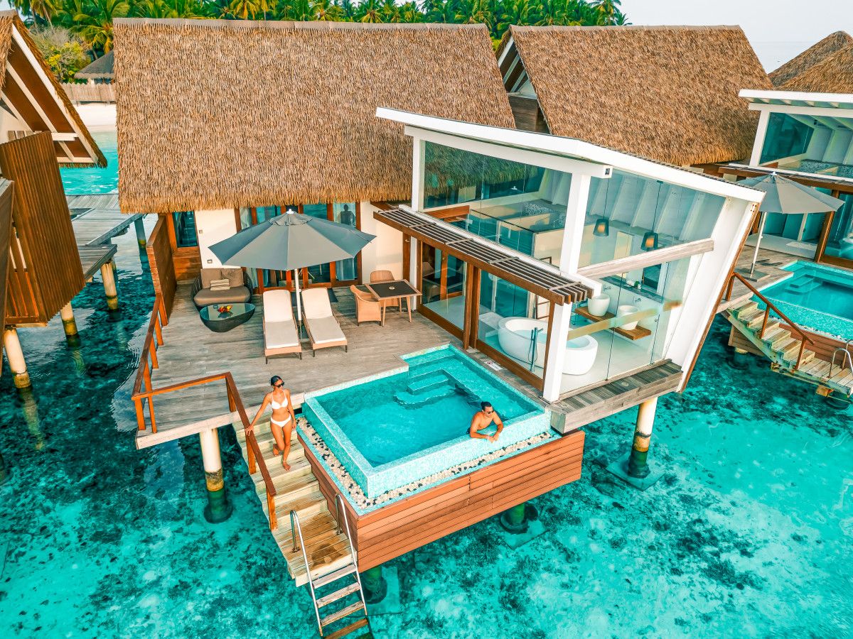 A couple relaxing at their overwater villa’s private pool
