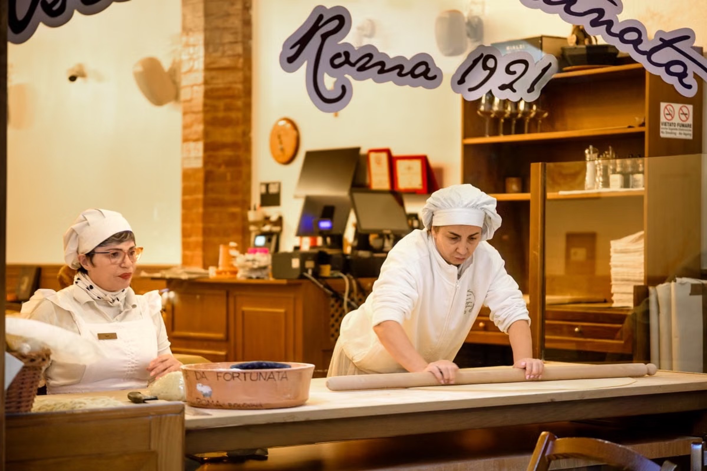 Cooks rolling fresh pasta dough by hand