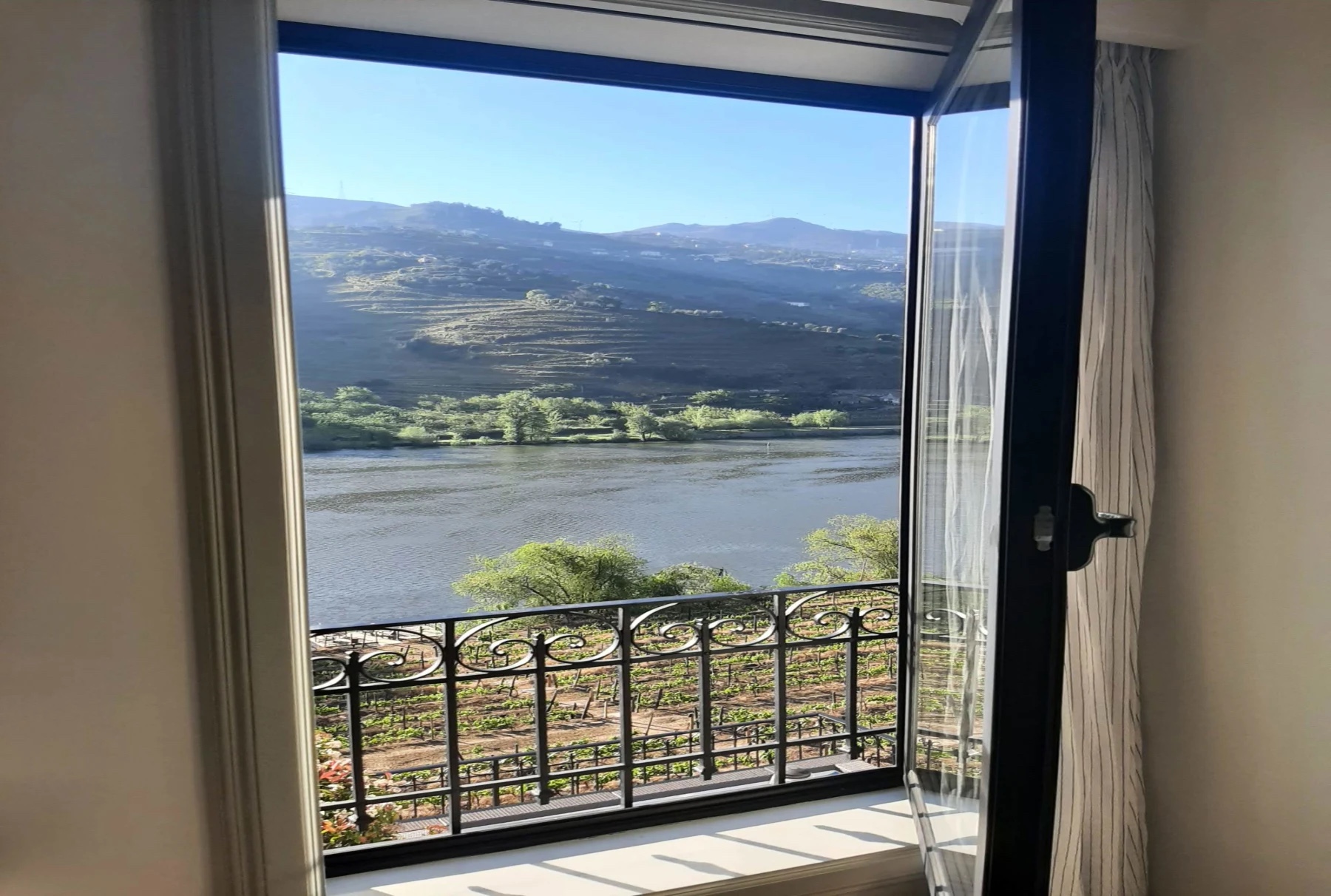 Hotel window opening onto a balcony above the terraced Douro Valley