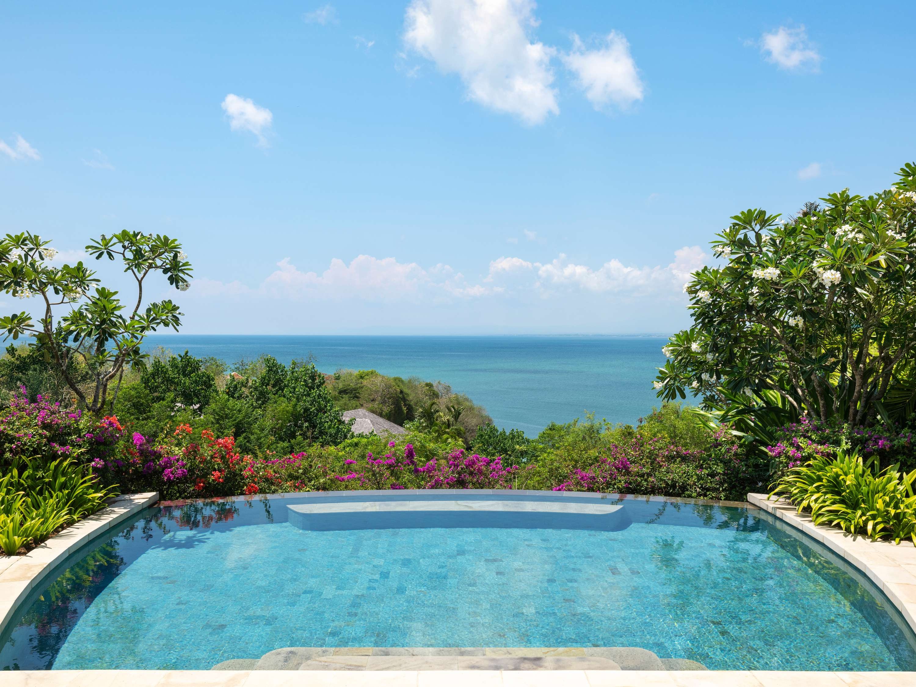 Infinity pool among frangipani trees looking out to the ocean in Bali