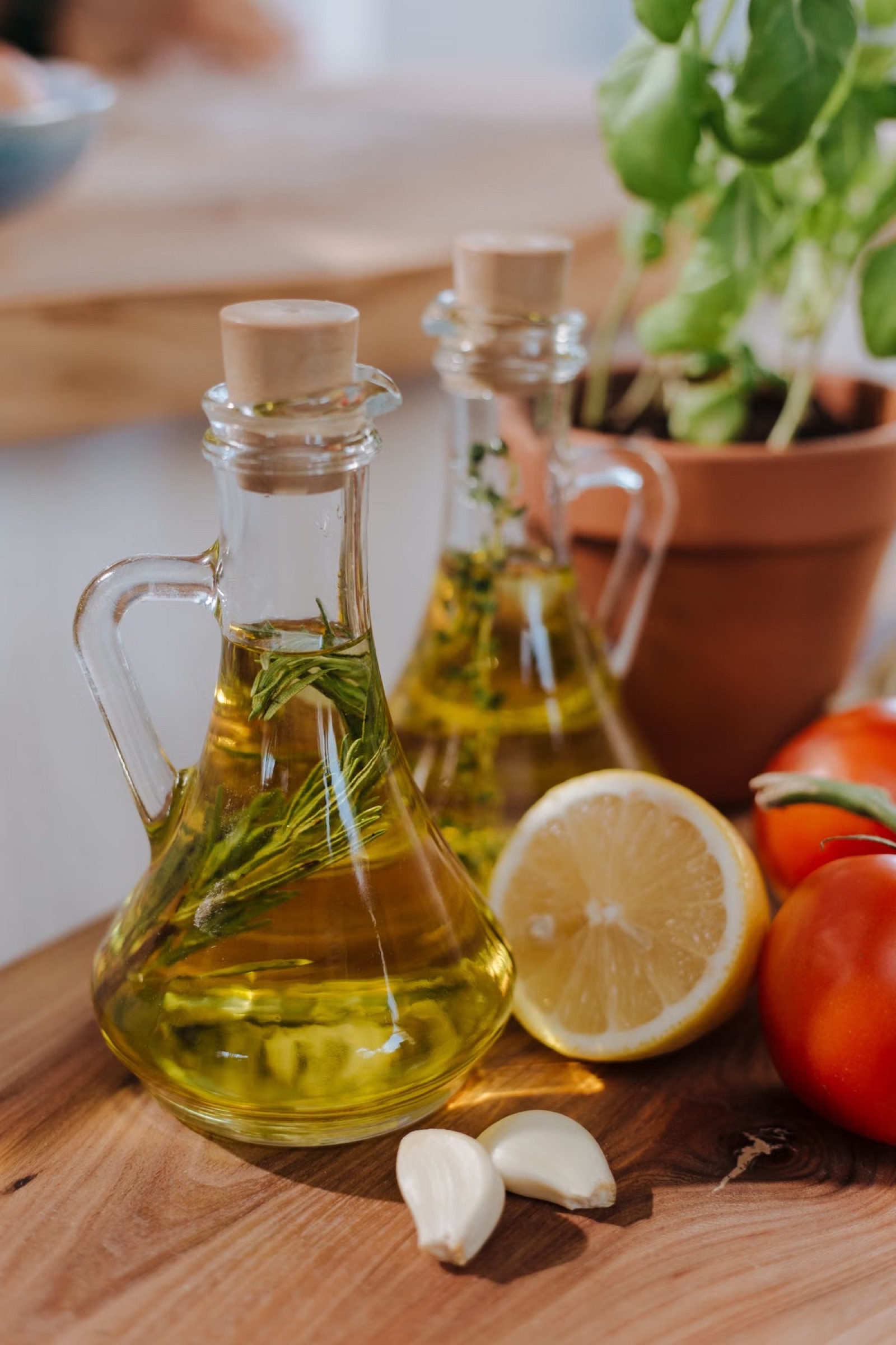 Bottles of olive oil with herbs, lemon and tomatoes