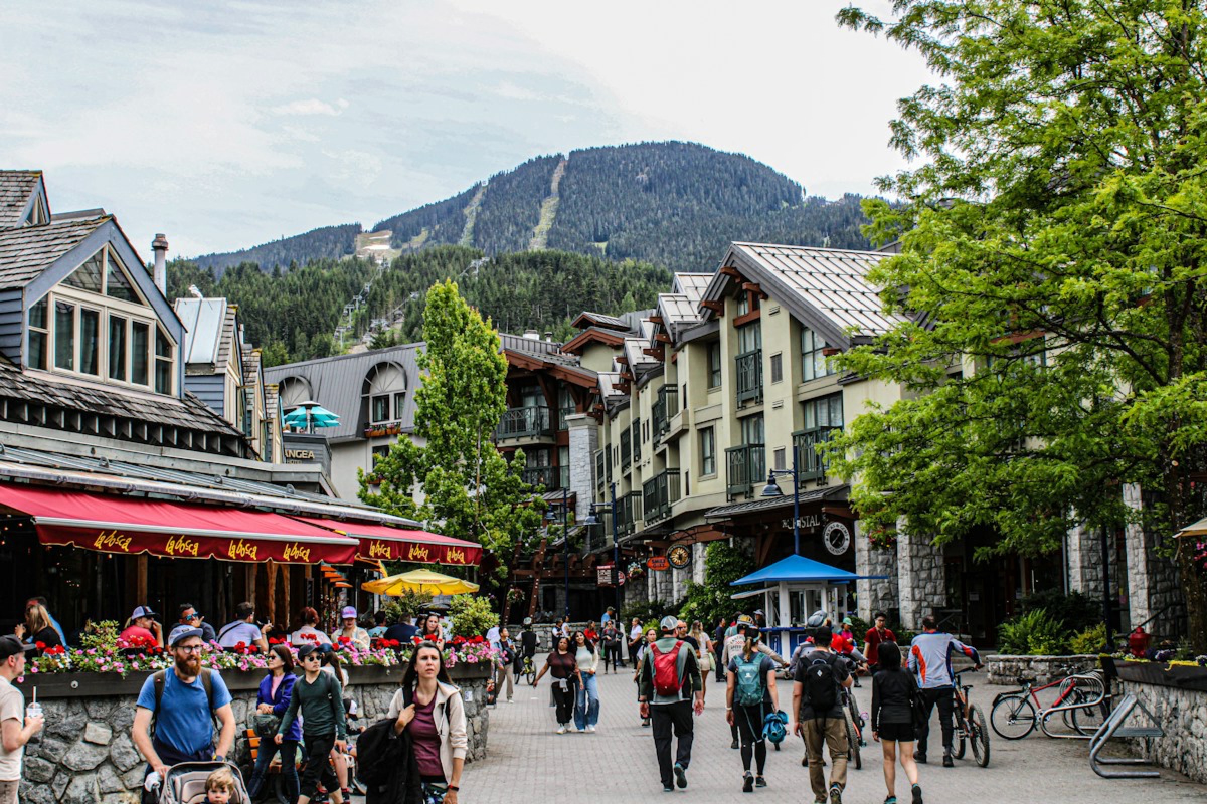 Walkers in Whistler Village beneath the mountains