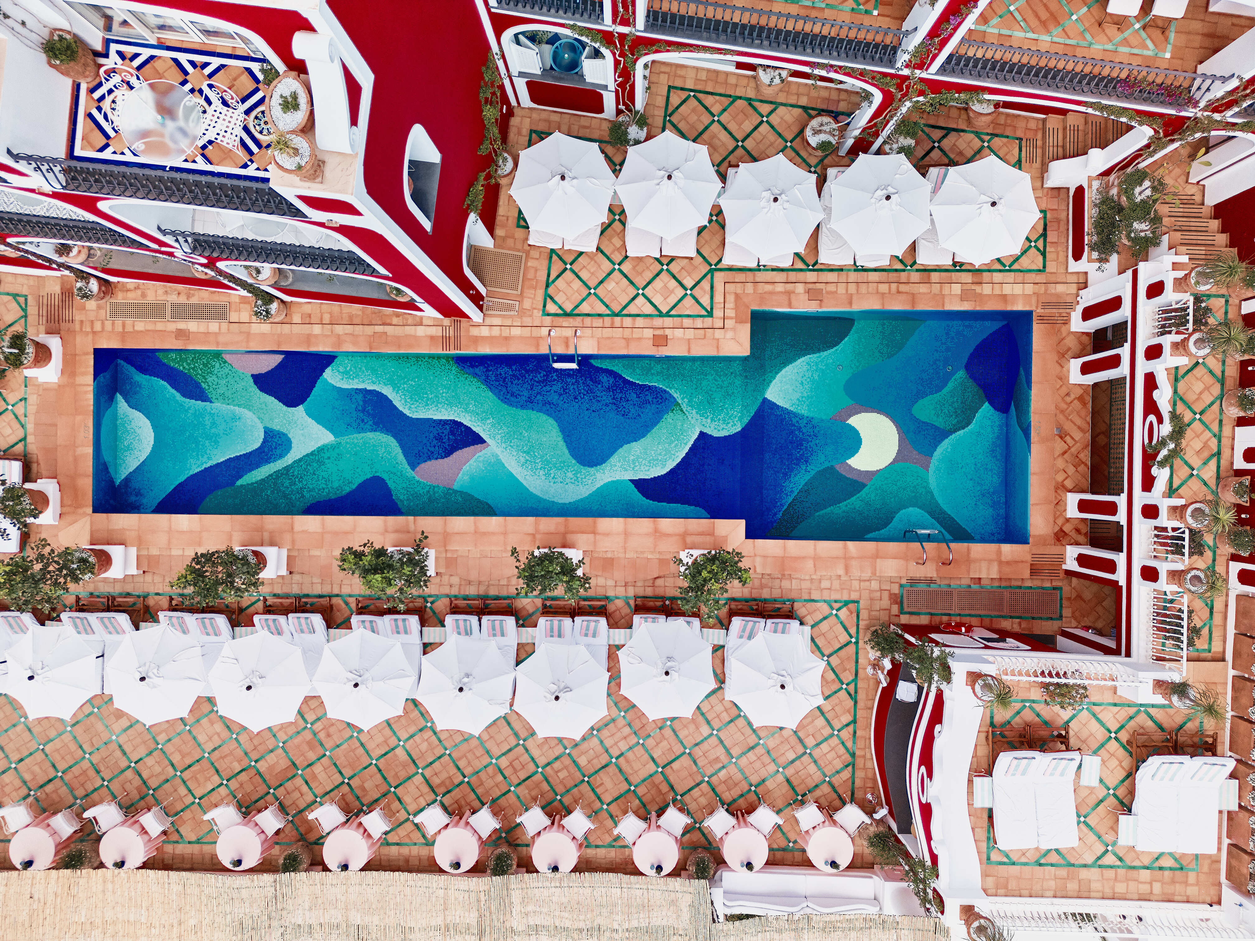 Looking down on a pool terrace lined with white umbrellas on the Amalfi Coast