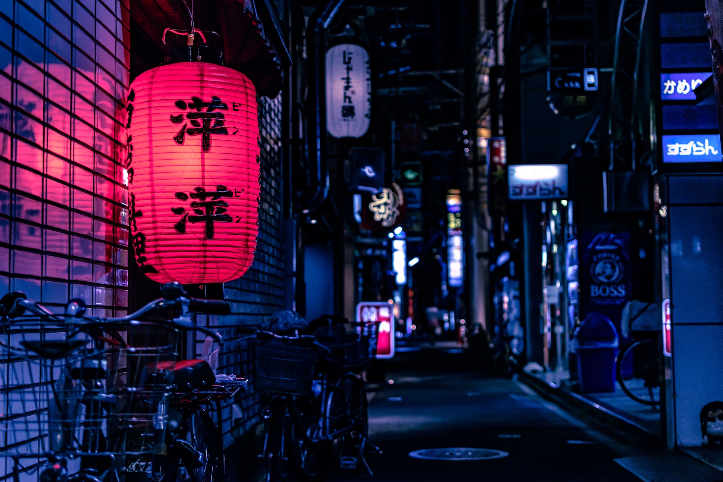 A red paper lantern glowing in a narrow Tokyo laneway at night