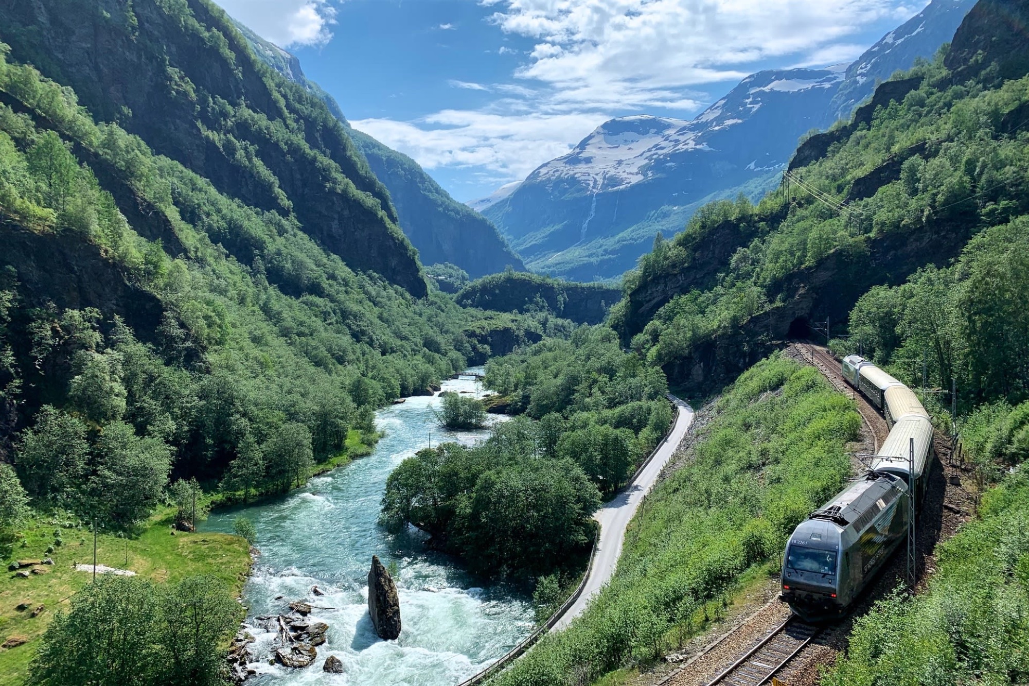 The Fl&aring;m Railway winding beside a river through a green mountain valley