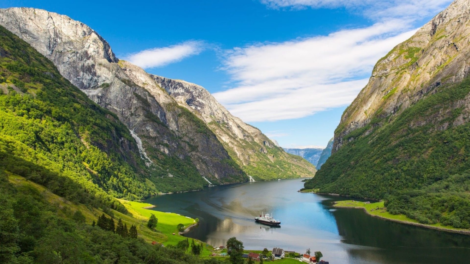 A small boat on the N&aelig;r&oslash;yfjord between steep green mountains